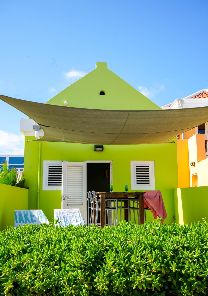 Green Caribbean house with white shutters and outdoor dining area in Pietermaai District, Curaçao