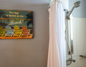 Simple and clean bathroom with shower and white curtain – Aqua apartment Curaçao