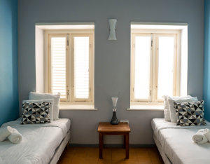Twin bedroom with decorative pillows and wooden floors – Aqua apartment Curaçao