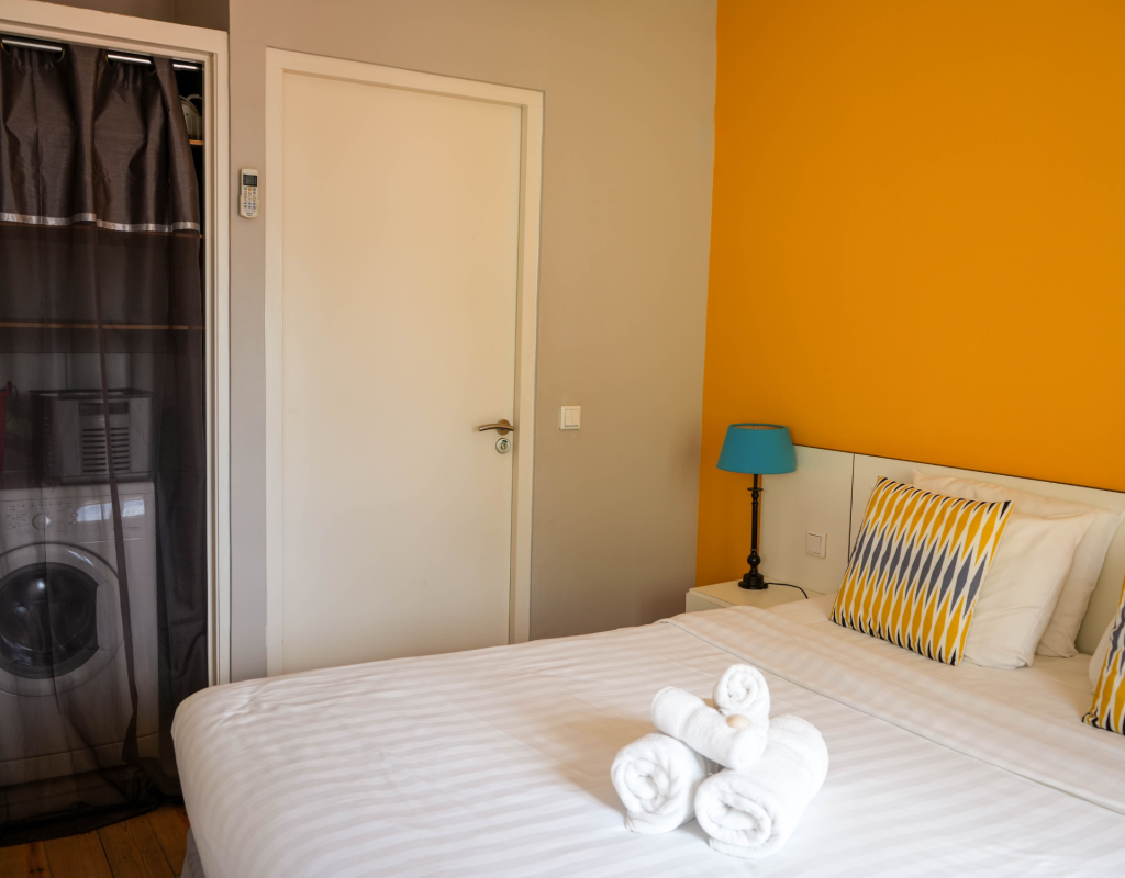 Minimalist bedroom with white walls and queen bed – Tierra apartment Curaçao