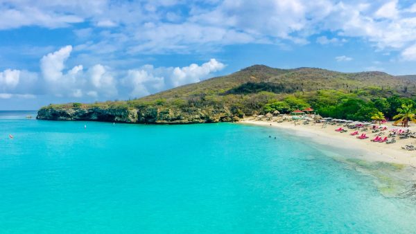 White sand beach and turquoise water in Curaçao with palm-fringed hills