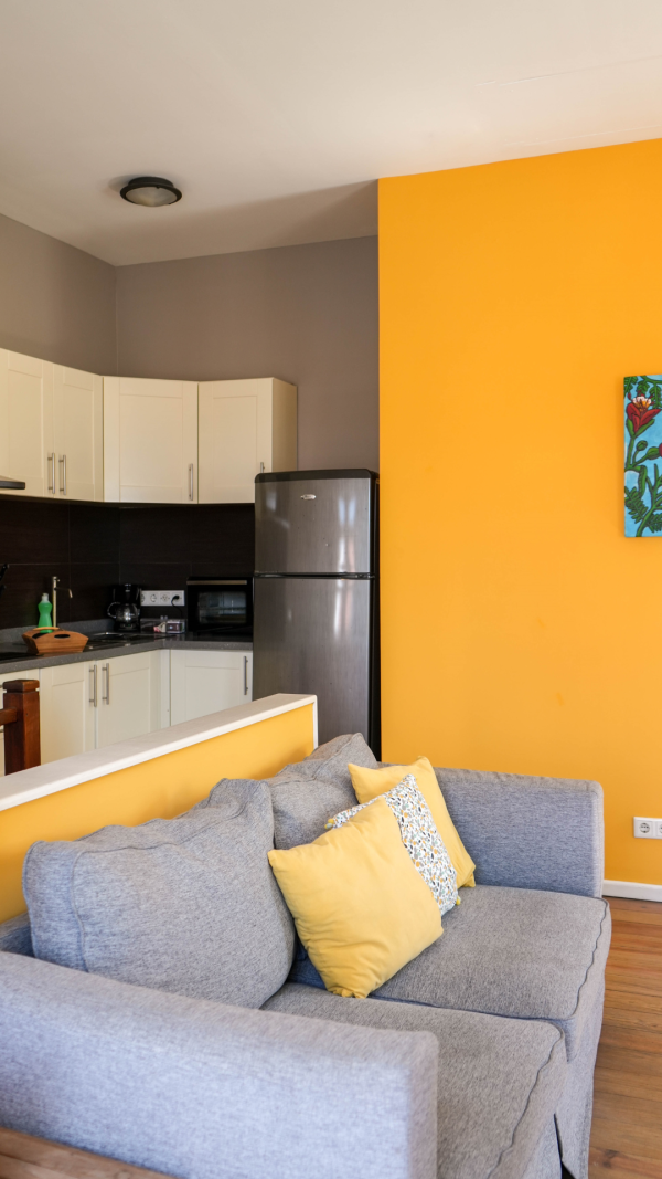 Tierra apartment living room with yellow accent wall and modern open kitchen – Dushi Pietermaai Apartments