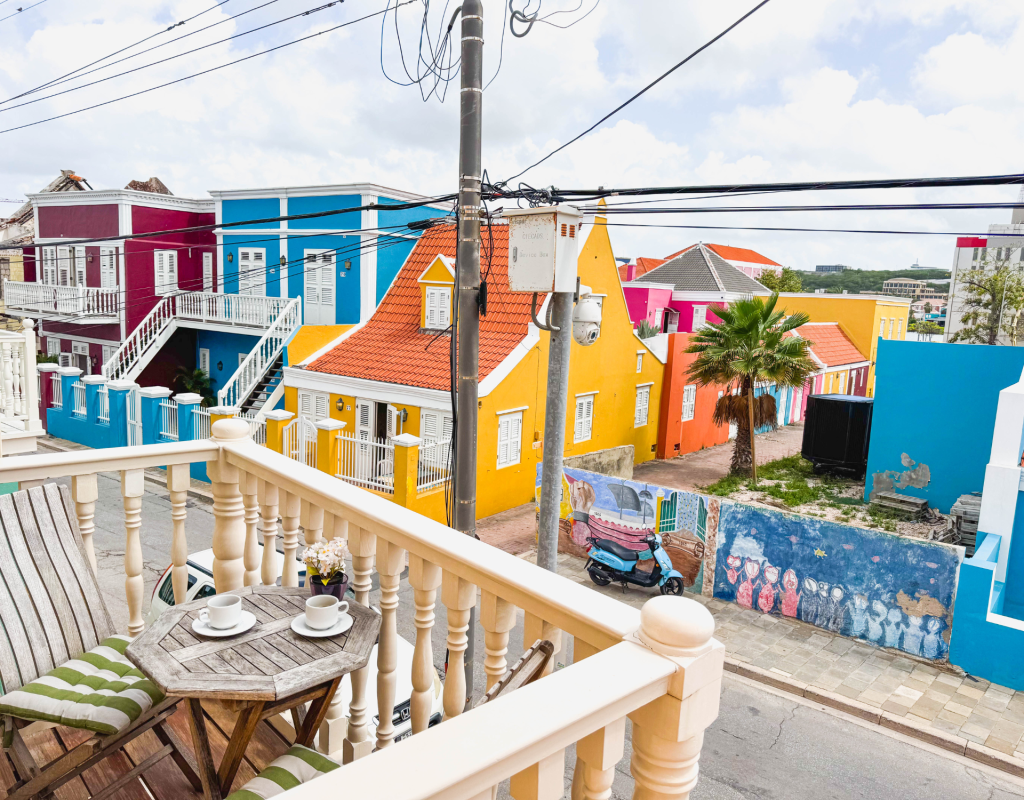 Colourful street view in Pietermaai from private apartment balcony with coffee table – Dushi Pietermaai Apartments